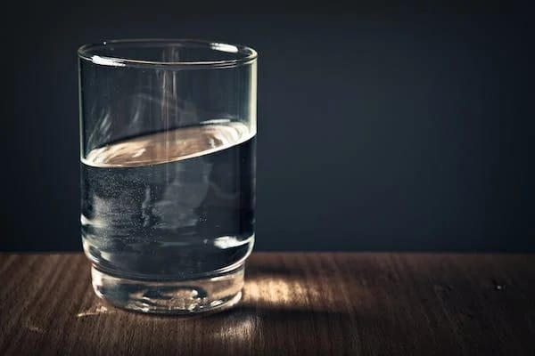 Image of a glass of water highlighted against a dark background on a table