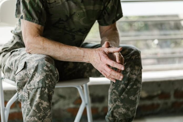Image of military veteran, not showing their face, with their hands together in contemplation