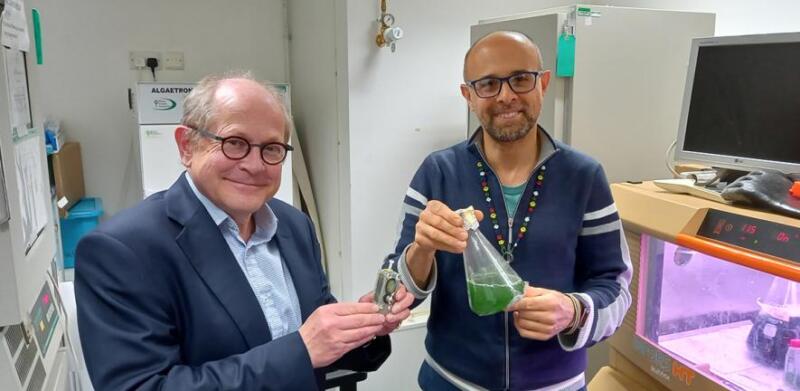Self Powered computer - Resaercher Howe holding the tiny computer with Dr. Bombelli holding flask of algae